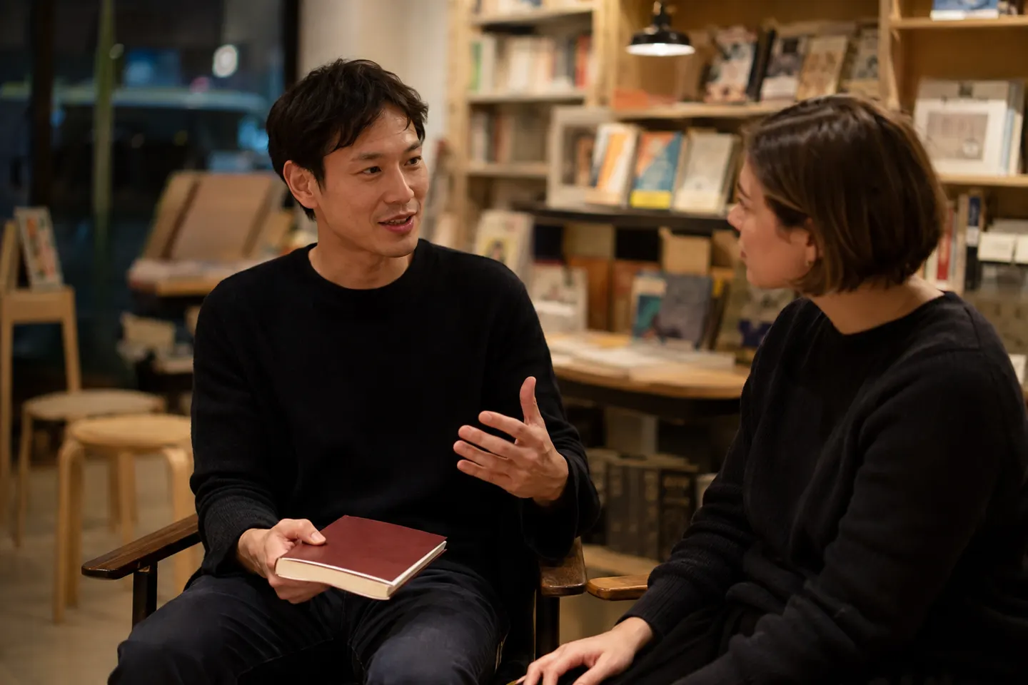 Two adult Japanese learners in a bookshop discussing the main idea after closing a short reader