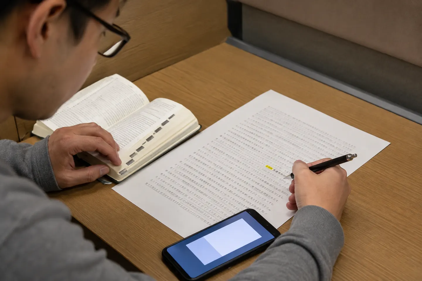 Adult learner checking one highlighted Japanese word in a dictionary while keeping the full passage open
